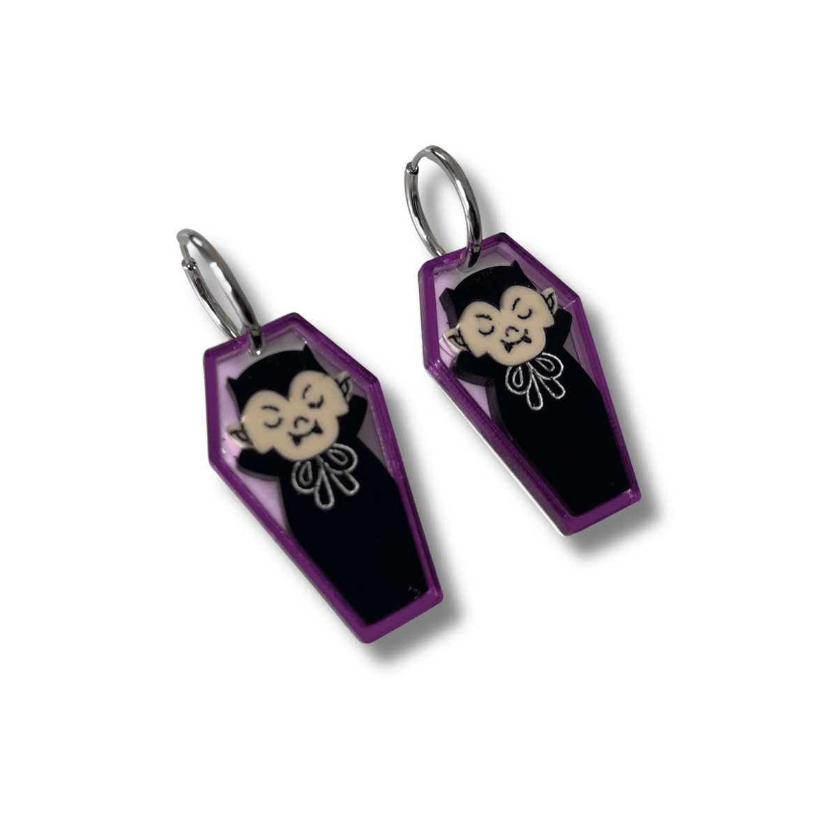 Pendientes de metacrilato morado con forma de ataúd y dibujo de vampiro con aros de acero inoxidable.